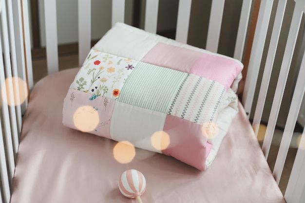 Kuscheliges Babybett mit rosa Patchworkdecke