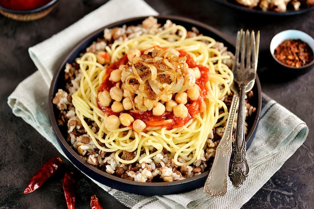 Kushari oder Koushari - ägyptisches Gericht aus Linsen, Reis, Nudeln, Kichererbsen mit Tomatensauce und knusprigen Zwiebeln. Arabische Küche