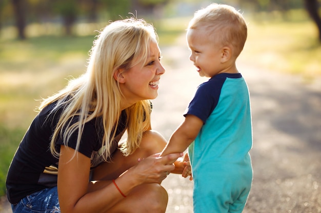 Kuss und Umarmungen von Mutter und Sohn. Mutter und Sohn gehen im Sommerpark spazieren.