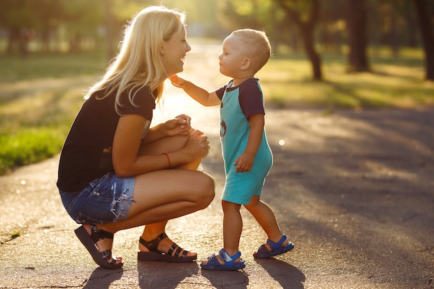 Kuss und Umarmungen von Mutter und Sohn. Mutter und Sohn gehen im Sommerpark spazieren.