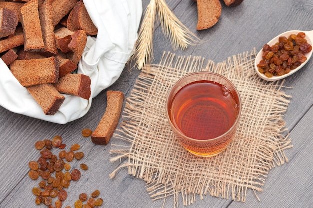 Kvas im Glas mit Roggenbrot und Rosinen auf hölzernem Hintergrund