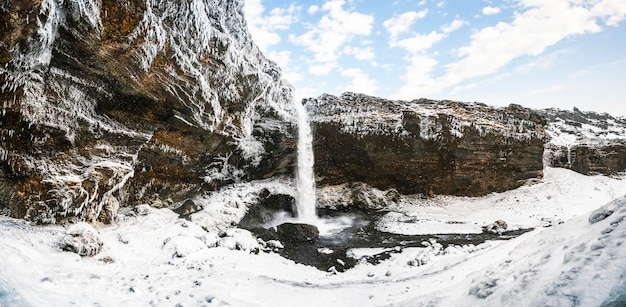 Kvernufoss-Wasserfall Island Isländische Winterlandschaft Hoher Wasserfall und Felsen Schnee und Eis