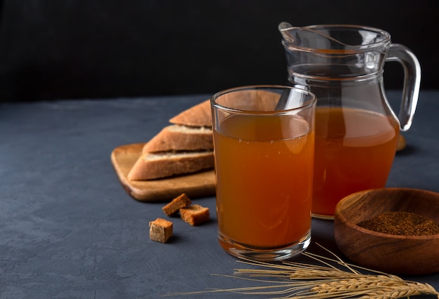 Kwas in einem Glas und einem Krug Roggenbrot