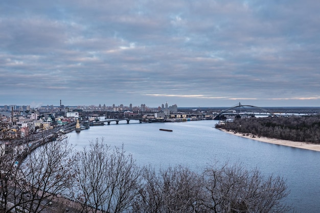 Foto kyiv, mañana de invierno, hermosa vista al centro histórico de podol. río dnipro, cielo nublado.