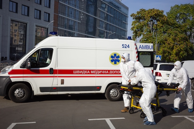 KYIV, UCRÂNIA - 12 de outubro de 2021: Equipe de ambulância transfere um paciente em uma maca de um carro para um hospital móvel durante a epidemia de COVID-19