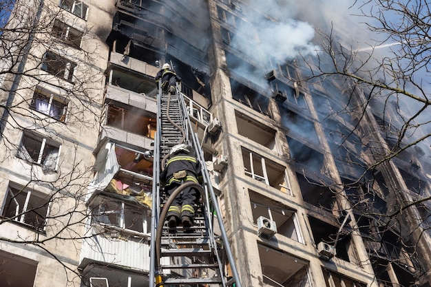 KYIV UCRÂNIA 15 de março de 2022 Guerra na Ucrânia Bombeiros combatendo um incêndio em um prédio residencial que foi atingido por um projétil russo