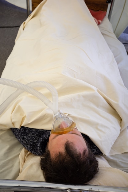 KYIV, UCRANIA - 12 de octubre de 2021: Activistas actúan con una escena del departamento de reanimación temporal para pacientes con COVID-19. Hombre con mascara de oxigeno