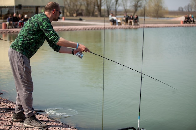 Kyiv, Ucrania 16 de abril de 2018. Pescador caucásico atrapa peces con una caña giratoria en el lago.