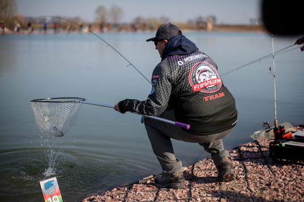 Kyiv, Ucrania 16 de abril de 2018. Un pescador caucásico atrapa peces con una red de aterrizaje en el lago.