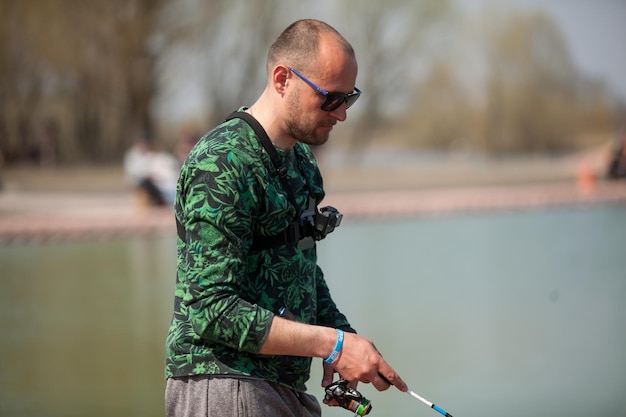 Kyiv, Ucrânia, 16 de abril de 2018. Pescador caucasiano pega peixe com uma vara de fiação no lago.