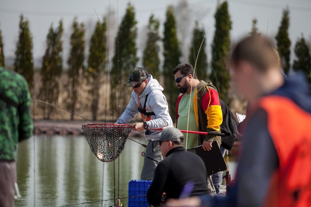 Foto kyiv, ucrânia, 16 de abril de 2018. um pescador com uma vara de fiação segura um peixe em uma rede de desembarque.