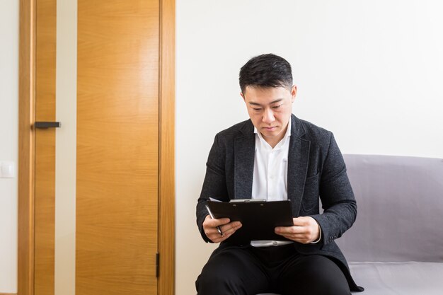 l hombre asiático esperando una entrevista de trabajo en la sala de espera del centro de oficinas