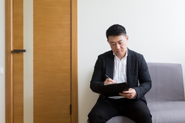 l hombre asiático esperando una entrevista de trabajo en la sala de espera del centro de oficinas