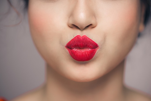 Lábios de mulher mandando um beijo com batom vermelho brilhante