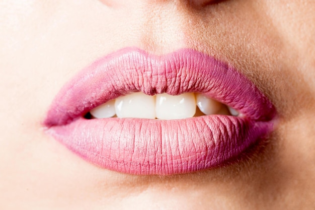 Los labios femeninos saturados están pintados en primer plano rosa. Encontrar tu propio estilo