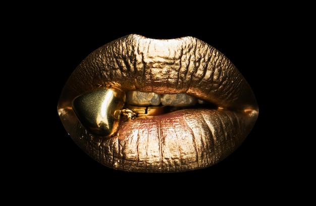 Los labios femeninos sexy de oro los labios hermosos la belleza de la mujer dorada el concepto de joyería de la boca