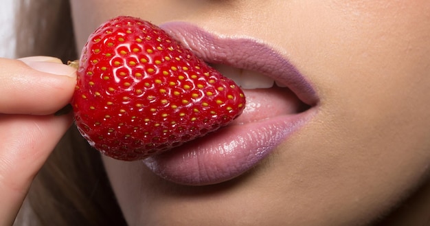 Lábios femininos comendo morango vermelho