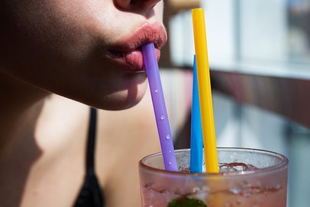 Lábios femininos tomando coquetéis e bebidas alcoólicas em bar