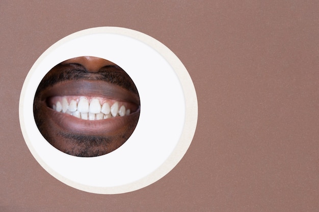 Labios de hombre afroamericano leerlo a través del círculo en fondo marrón