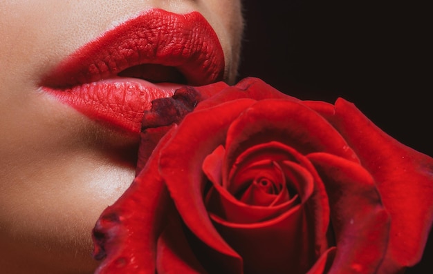 Labios con lápiz labial mujer de primer plano con macro rosa roja sobre fondo negro labios de mujer hermosa con rosa