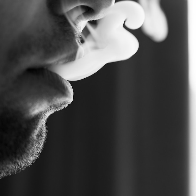 Lábios masculinos sedutores soprando fumaça de cigarro