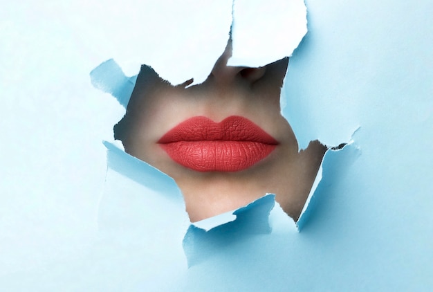 Labios rojos y fondo de papel rasgado azul