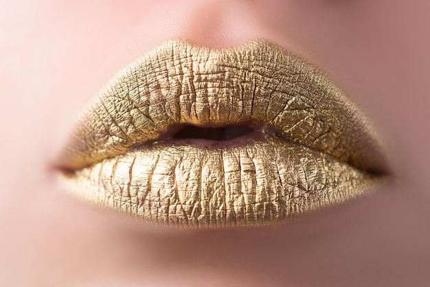 Labios sensuales. Closeup sexy hermosa mujer labios dorados aislados. Lápiz labial dorado.