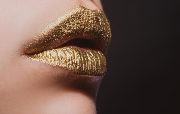 Labios sensuales. Closeup sexy hermosos labios dorados femeninos aislados. Lápiz labial dorado.