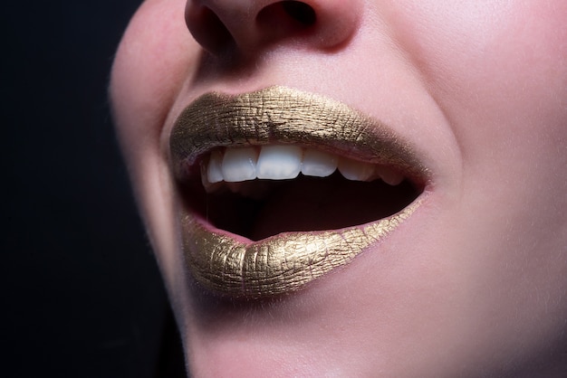 Labios sonrientes closeup sexy hermosa mujer labios dorados aislado lápiz labial de oro