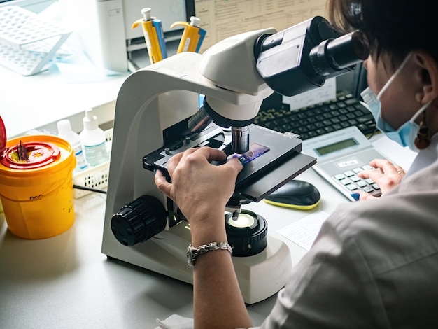 Laboratorio de desarrollo médico Científica caucásica mirando bajo el microscopio