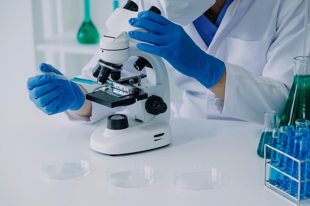 Laboratorio de desarrollo médico Científica caucásica que mira bajo el microscopio analiza especialistas en muestras de placas de Petri que trabajan en investigación de biotecnología médica en laboratorio farmacéutico avanzado