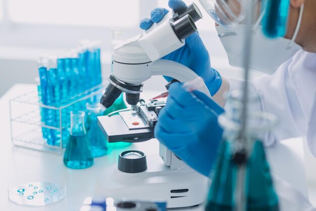 Laboratorio de desarrollo médico Científica caucásica que mira bajo el microscopio analiza especialistas en muestras de placas de Petri que trabajan en investigación de biotecnología médica en laboratorio farmacéutico avanzado