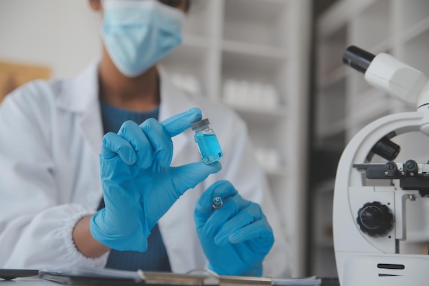 Laboratório profissional Incrível trabalhador médico de cabelos compridos vestindo uniforme enquanto usa microscópio durante a pesquisa