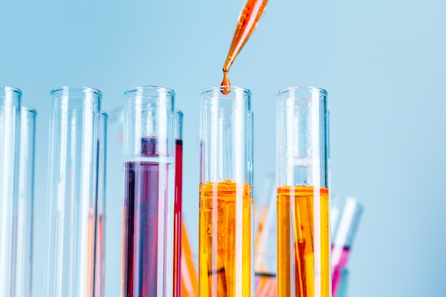 Laborreagenzgläser mit roten und gelben Flüssigkeiten auf hellblauem Hintergrund