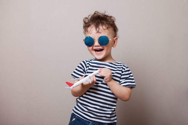 Lachend, fröhliches Baby, Kleinkind mit einem kleinen Flugzeug in den Händen.