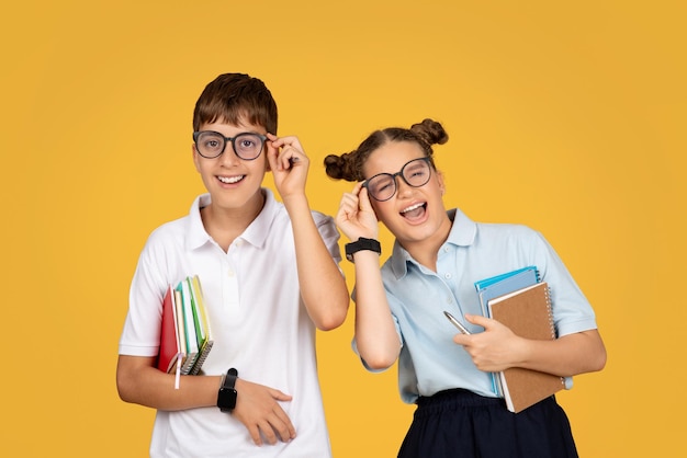 Lachende europäische Teenager-Schulkinder in Gläsern mit Büchern haben Spaß in der Schule und genießen Bildung