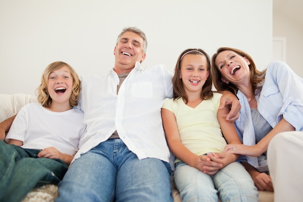 Lachende Familie, die auf dem Sofa sitzt