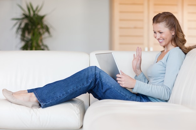 Lachende Frau mit ihrem Notebook auf dem Sofa