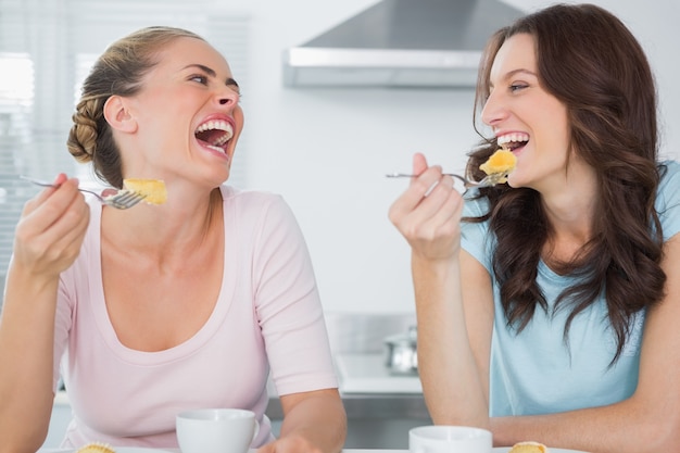 Lachende Freunde, die Kuchen essen und Kaffee trinken