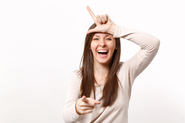 Lachende junge Frau in leichter Kleidung, die eine lockerere Geste zeigt, die den Zeigefinger auf die Kamera zeigt, isoliert auf weißem Wandhintergrund im Studio. Menschen aufrichtige Emotionen Lifestyle-Konzept. Mock-up-Kopienbereich.
