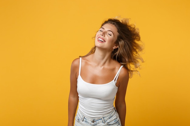 Lachende junge Frau Mädchen in leichter Freizeitkleidung isoliert auf gelb-orangeem Wandhintergrund Studioporträt. Menschen aufrichtige Emotionen Lifestyle-Konzept. Mock-up-Kopienbereich. Posieren mit fliegenden Haaren.
