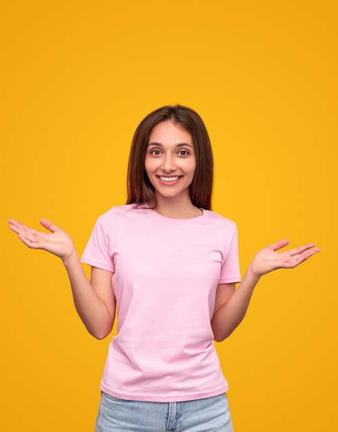 Lachende moderne Brünette im rosa T-Shirt, das Palmen in Überraschung auf Gelb hochhält