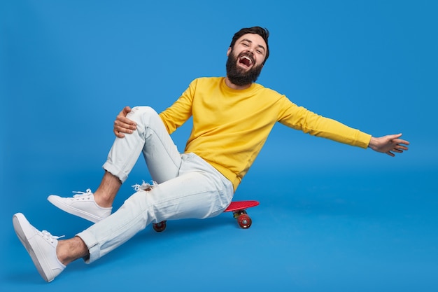 Lachender Mann, der auf Skateboard sitzt