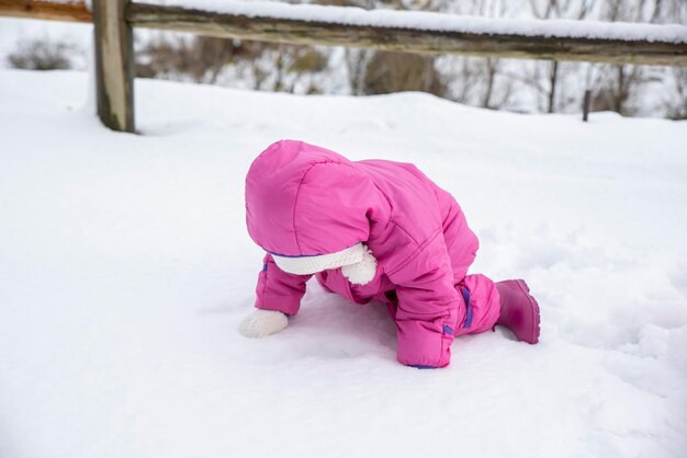 Lachendes Babymädchen, das im Tiefschnee liegt