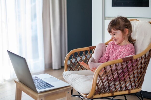 Lachendes kleines Mädchen im Video-Chat mit ihren Großeltern am Laptop