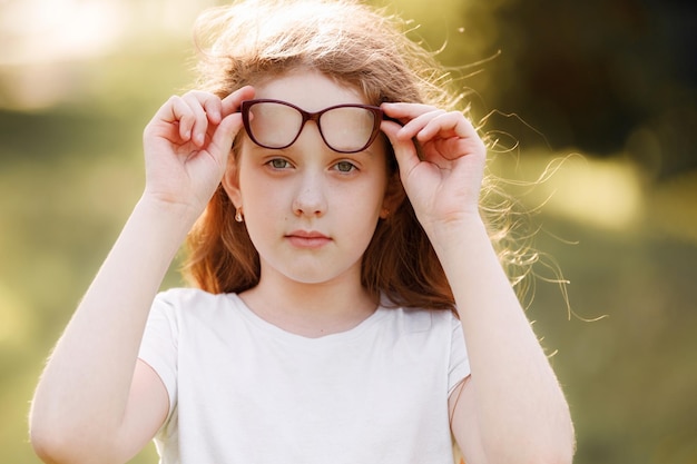 Lachendes kleines Mädchen mit Brille im Frühlingspark