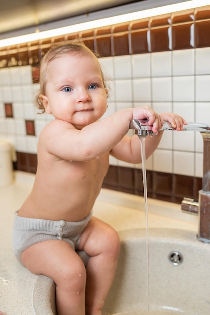 Lachendes kleines Mädchen nimmt Hygienemaßnahmen im Waschbecken in der Küche vor