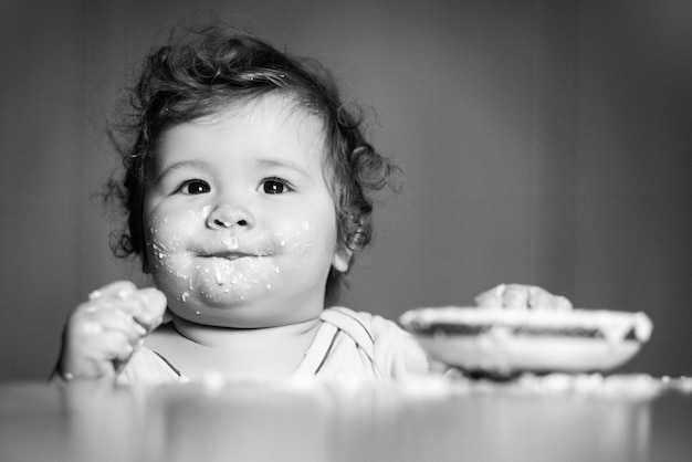 Lachendes lustiges Baby mit schmutzigem Essensgesicht glücklicher Kinderlöffel isst sich