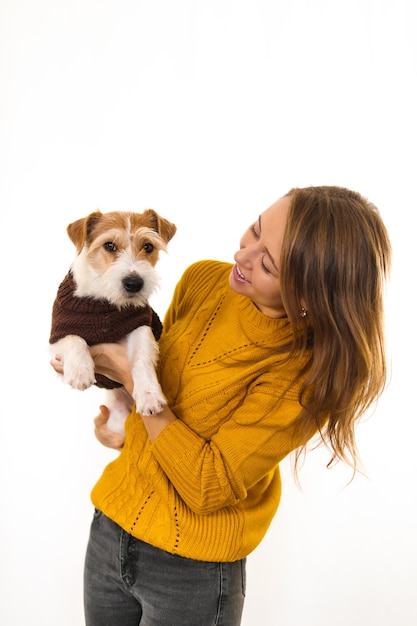 Lachendes Mädchen in einer gelben Jacke hält einen Hund in ihren Armen. Auf weißem Hintergrund isolieren