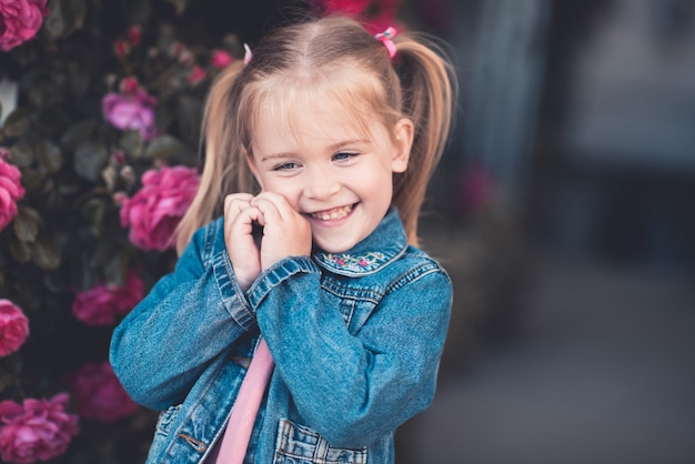 Lachendes Mädchen mit Jeansjacke posiert über Rosen